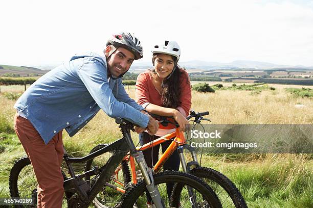 Young Couple Riding Bicycles In The Countryside Stock Photo - Download Image Now - Cycling, Helmet, Bicycle