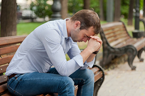 istock Man sitting in a public garden on a bench with his head down 465140485
