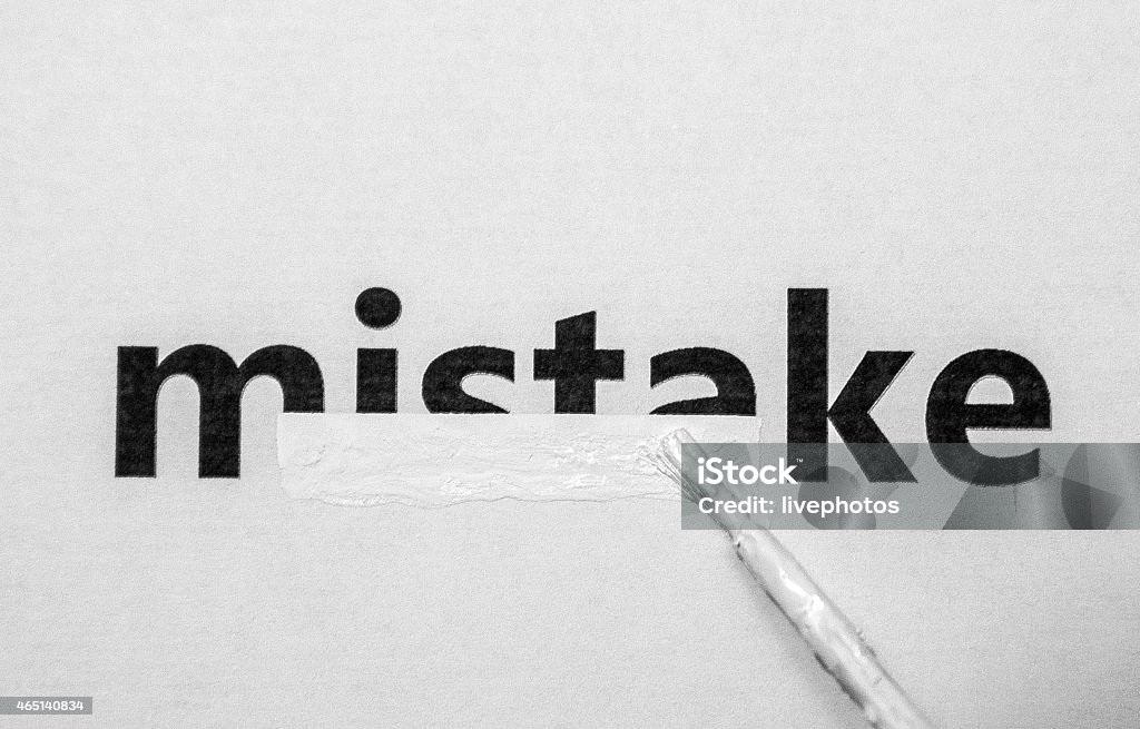 A paintbrush covering up mistake with white paint erase Correction Fluid Stock Photo