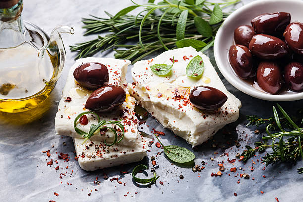 Feta cheese with olives Feta cheese with olives and green herbs on gray marble background greek food stock pictures, royalty-free photos & images