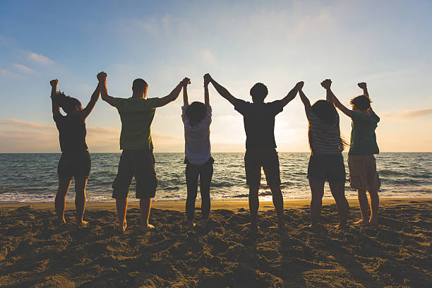 istock Multiracial group of people with raised arms looking at sunset 465142448