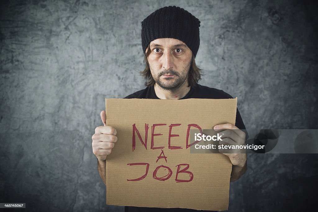 Man holding cardboard paper with Need a Job message Man holding cardboard paper with Need a Job message. Job seeking, unemployment issues. Chalkboard - Visual Aid Stock Photo