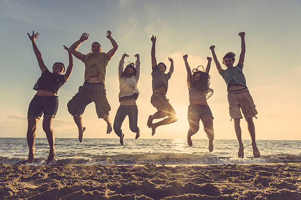 istock Multiracial group of people jumping at beach 465145318