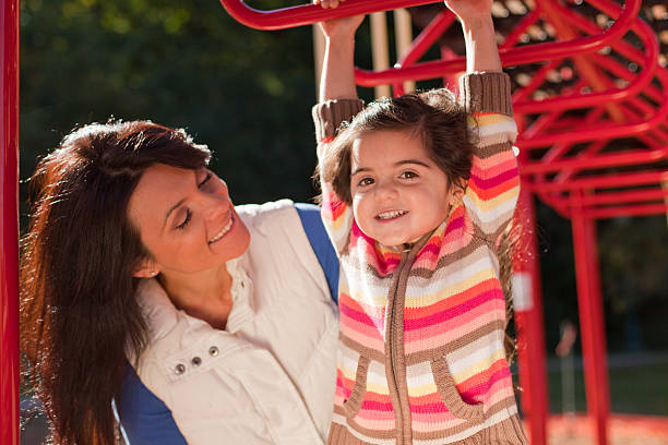 mom and daughter playing on jungle gym 6 stock photo