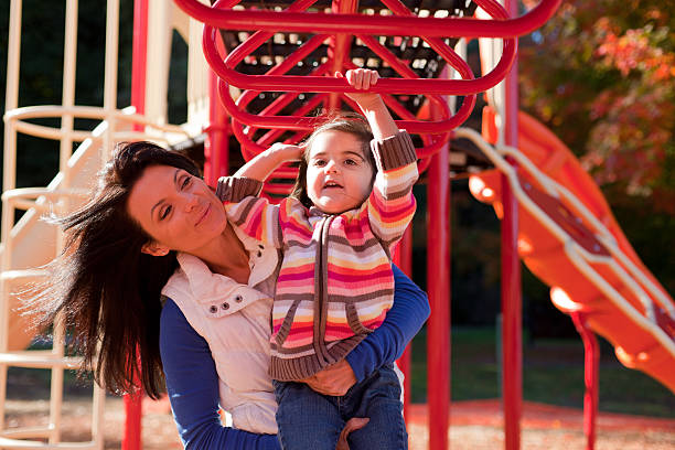 mom and daughter playing on jungle gym 4 stock photo