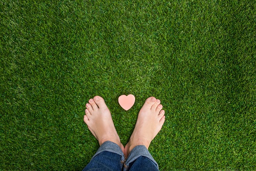 Mens feet standing on grass with small heart