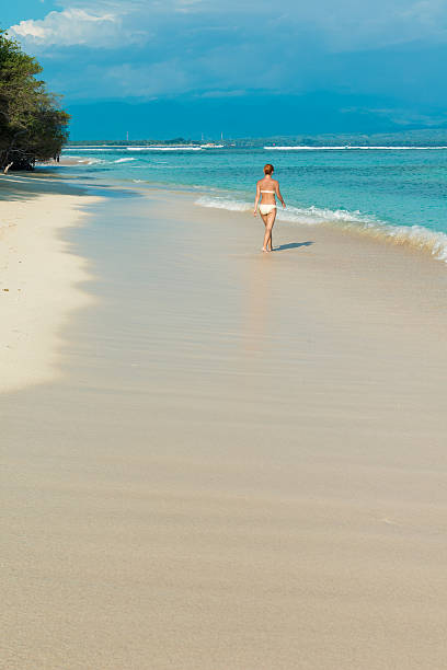istock Young woman walking along tropical beach 465150064