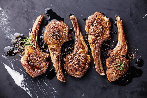 Roasted lamb ribs with spices on black marble background