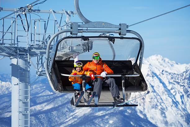 istock Father and boy sit in ski lift over mountains 465151088