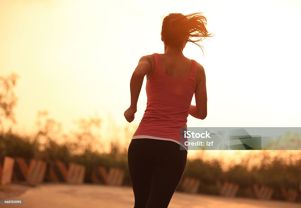 Woman going for a morning run at sunrise healthy sporty woman morning exercise running on mountain driveway under sunrise Active Lifestyle Stock Photo