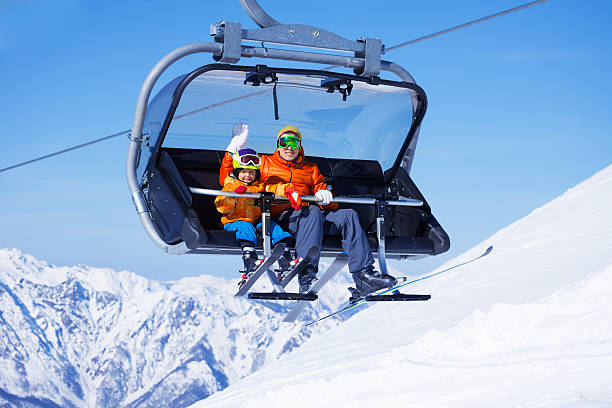 istock Boy and dad sit in chair lifting on the mountain 465151098