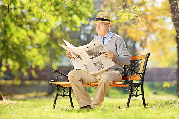 istock Senior man sitting on bench and reading a newspaper 465152883