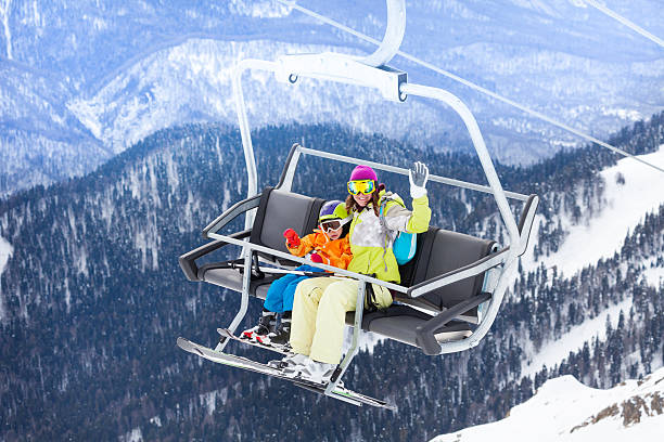 istock Happy boy with mother sit on skilift ropeway chair 465153756