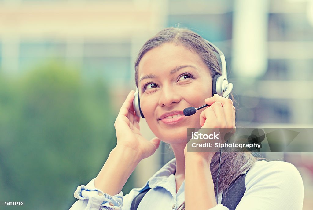 customer service representative, call center agent Closeup portrait smiling young female customer service representative, call center agent, support staff, operator with phone headset isolated on background with trees, city buildings. Face expression Centre - France Stock Photo