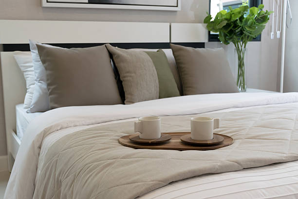 Modern double bed with beautiful light gray synthetic fur blanket and serving tray