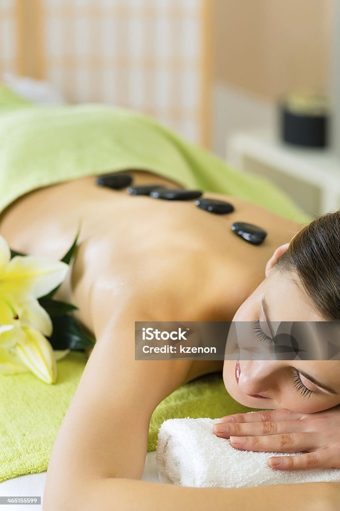 woman having wellness hot stone massage Beautiful woman having a wellness hot stone back massage Adult Stock Photo