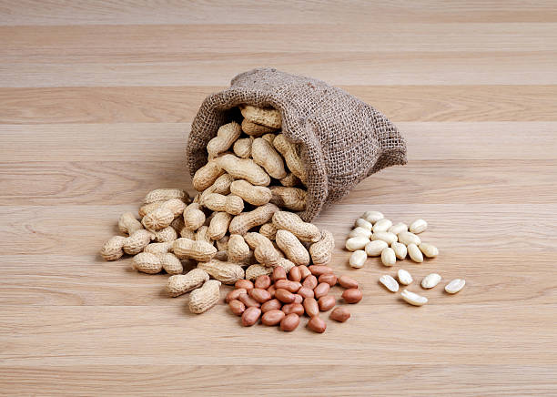 istock Peanuts in the bag sack isolated on wooden table 465156298