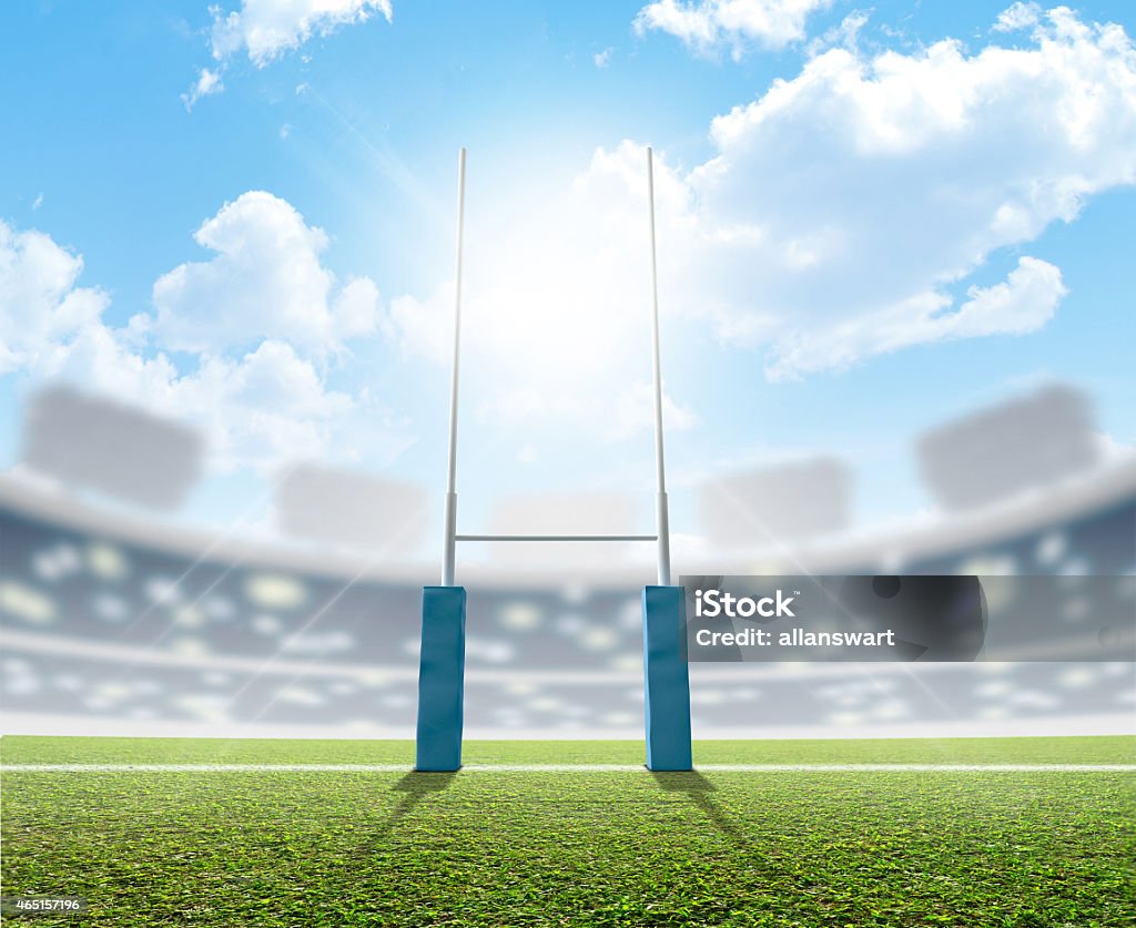 Rugby posts in a bright sunny stadium A rugby stadium with rugby posts on a marked green grass pitch in the daytime under a blue sky Rugby Field Stock Photo
