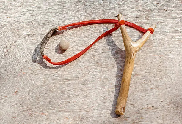 The old slingshot and clay pellet on old wood background, children toy.