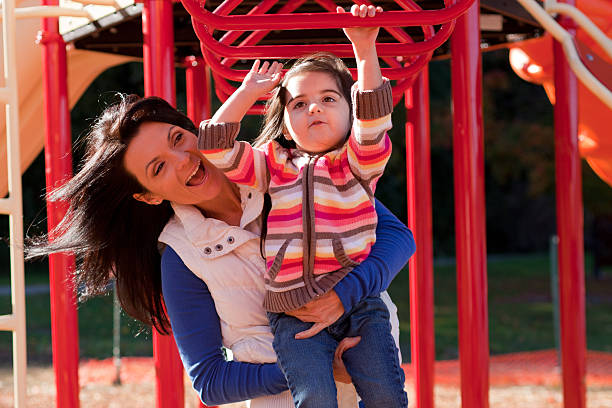 mom and daughter playing on jungle gym 3 stock photo