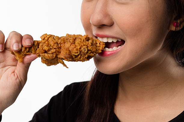 istock young girl holding, eating fried chicken 465160798