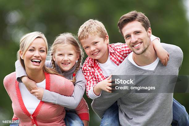 Parents Giving Children Piggybacks In Countryside Stock Photo - Download Image Now - Young Family, Family, Family with Two Children