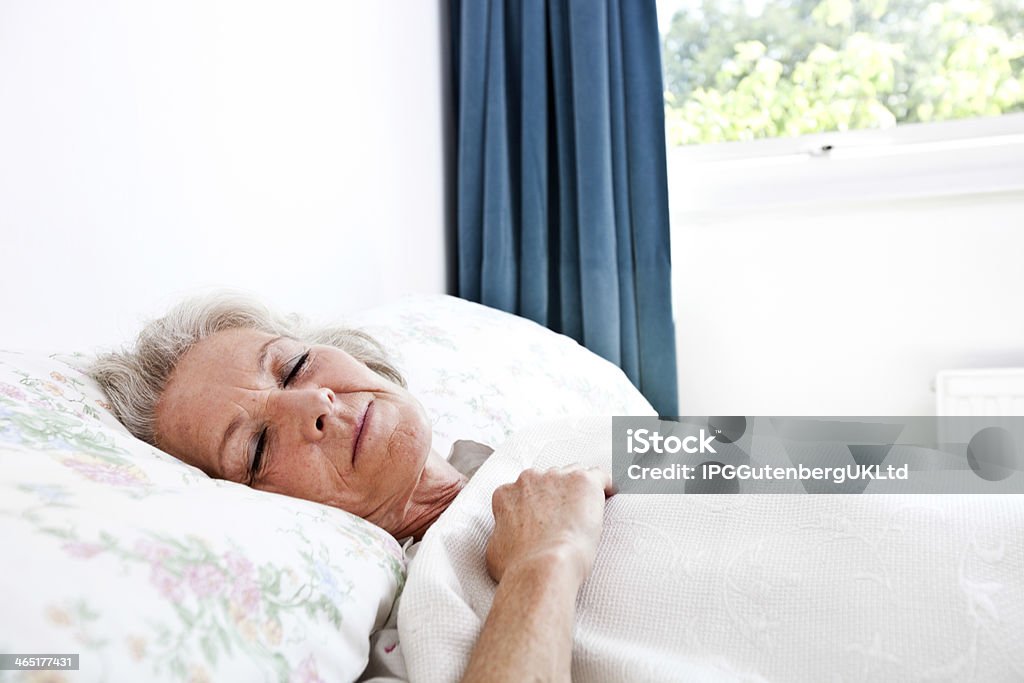 Senior Mujer durmiendo en el dormitorio como en su hogar - Foto de stock de 60-69 años libre de derechos