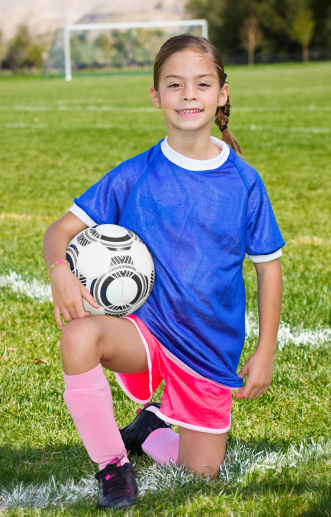 A portrait of a cute little soccer player with the field and goal in the background