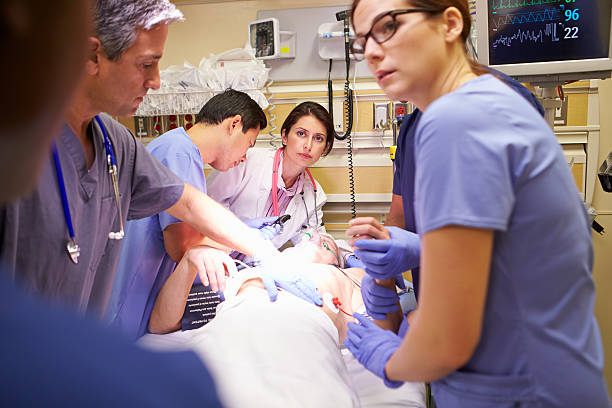 Medical team of five people working on a patient in ER Hard Working Medical Team Working On Patient In Emergency Room emergency room stock pictures, royalty-free photos & images