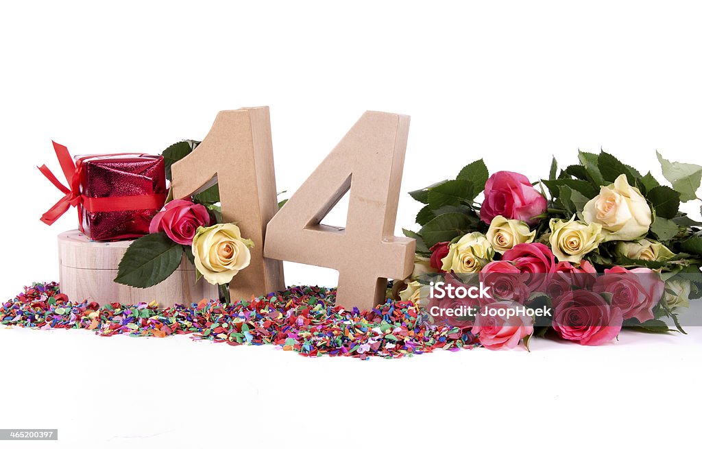 Age in figures, decorated with roses Number of age in a colorful studio setting with fresh roses on a bottom of confetti 14-15 Years Stock Photo