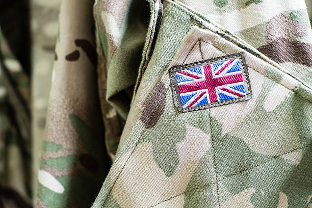Union Jack flag on sleeve of British military camouflage uniform Union Jack flag on the sleeve of British military camouflage uniform shirt sleeve british culture stock pictures, royalty-free photos & images