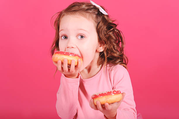 istock Cute baby girl eating donuts 465205521