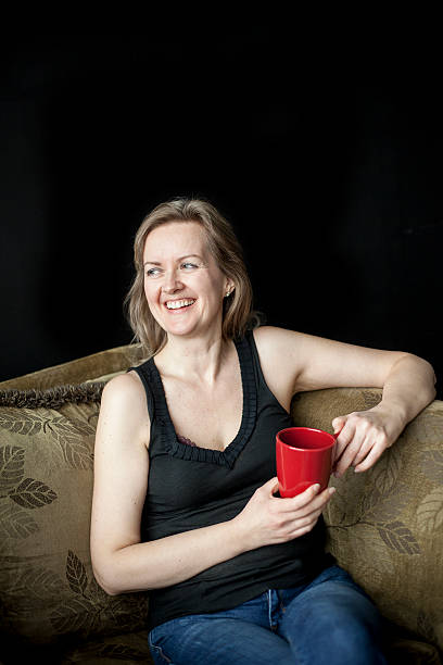 femme rire blonde avec rouge une tasse de café sur fond noir - the human body photos photos et images de collection