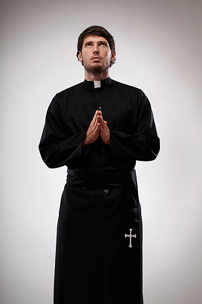 Young monk wearing black cassock is prying to God and saying thankyou