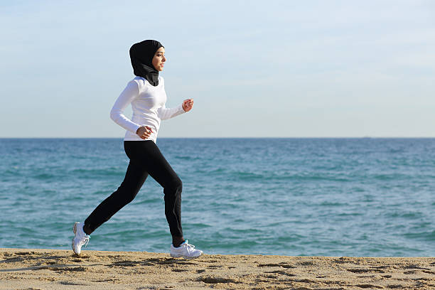 arab saudi corredor de mujer corriendo en la playa - women islam middle eastern ethnicity arabic style fotografías e imágenes de stock