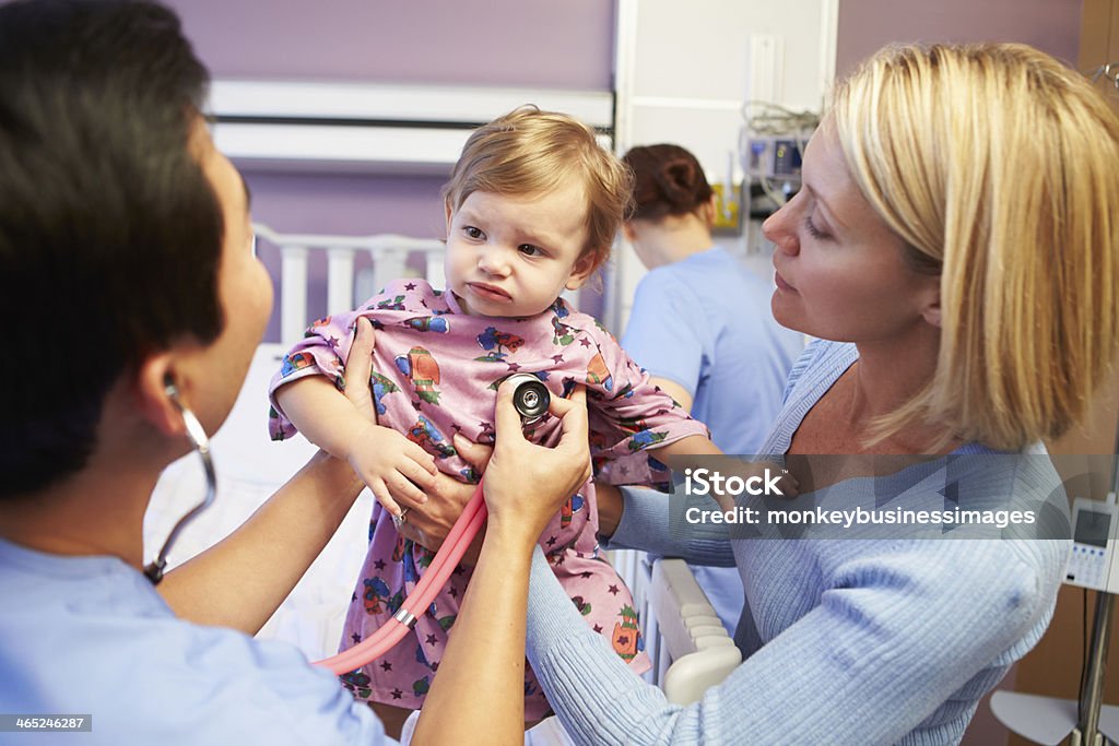 Mother holding her daughter during a medical examination Mother And Wearing Pyjamas Daughter With Staff In Pediatric Ward Of Hospital Child Stock Photo