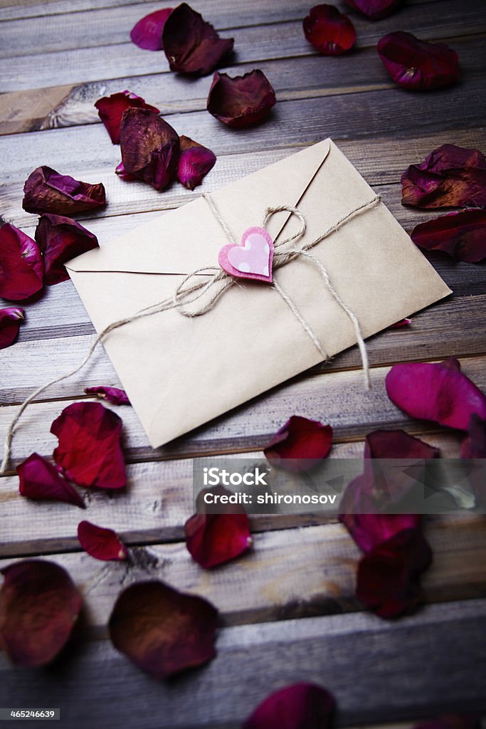 Love message Image of letter of love with small pink heart surrounded by rose petals Abstract Stock Photo