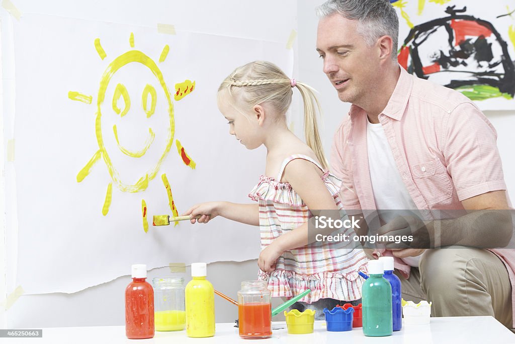 Teacher And Pupil In Pre School Art Class Teacher And Pupil In Pre School Art Class Painting On Wall 30-39 Years Stock Photo