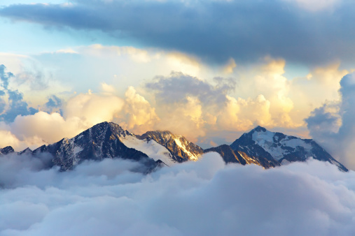 alpine landscape with peaks covered by snow and clouds