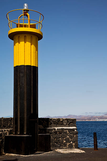 lighthouse and h   arrecife teguise lanzarote spain lighthouse and harbor pier boat in the blue sky   arrecife teguise lanzarote spain. yacht rock music stock pictures, royalty-free photos & images