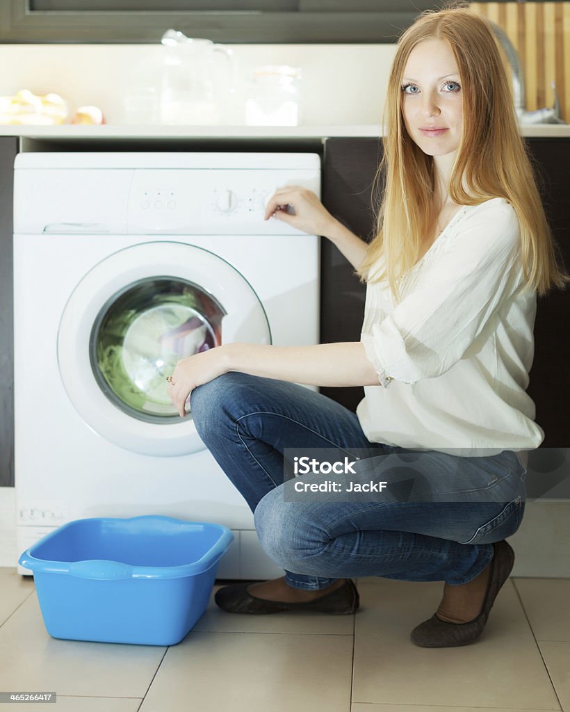 Blonde woman using washing machine at home Home laundry. Blonde woman using washing machine at home 20-29 Years Stock Photo