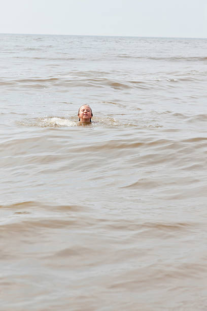 istock Kid boy having fun in the ocean with waves. 465267647