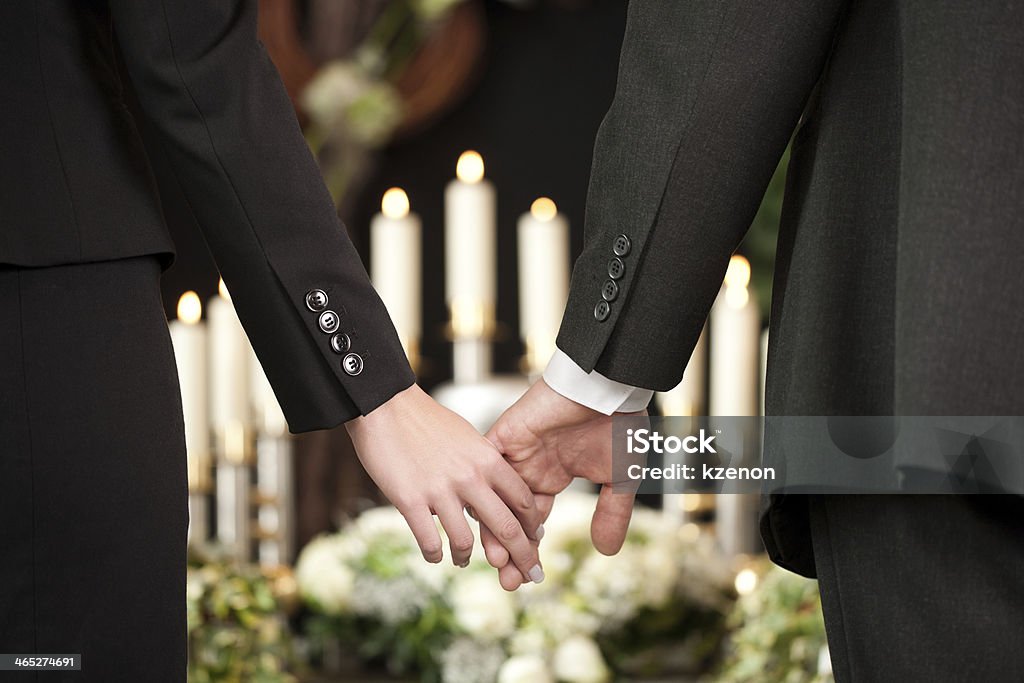 People at a funeral holding hands Religion, death and dolor  - couple at funeral holding hands consoling each other in view of the loss Funeral Stock Photo