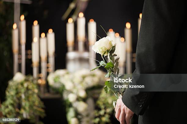 Man Holding A White Rose In Front Of Urn At Funeral Stock Photo - Download Image Now