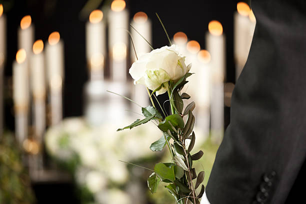 Grief - man with white roses at urn funeral Religion, death and dolor  - man at funeral with white rose mourning the dead funeral parlor photos stock pictures, royalty-free photos & images
