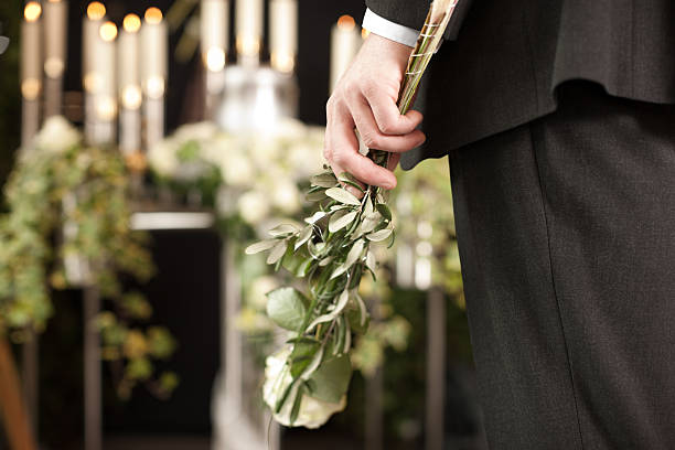 istock Grief - man with white roses at urn funeral 465280283