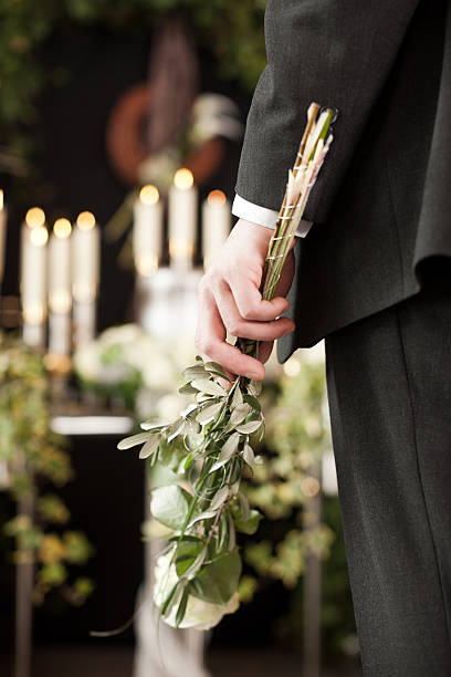 istock Grief - man with white roses at urn funeral 465280287