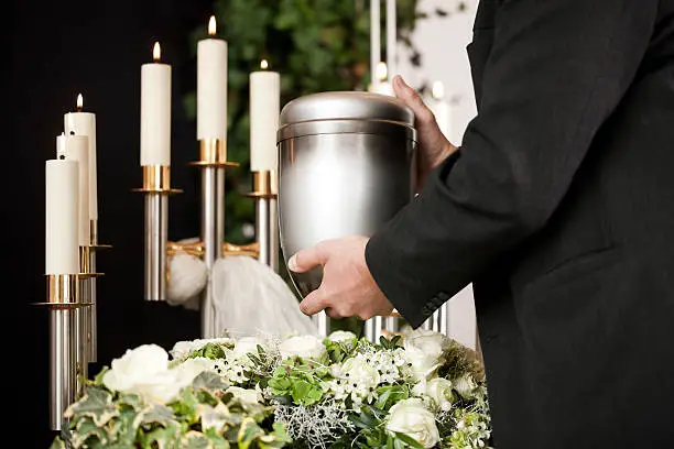 Religion, death and dolor  - mortician on funeral with urn