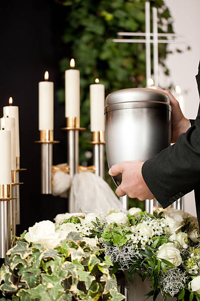 istock Man holding urn with candles and flowers 465280305