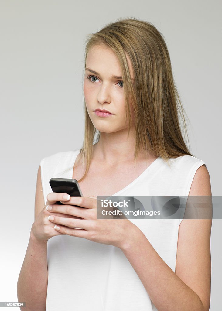 Teenage Girl Being Bullied By Text Message On Mobile Phone Studio Shot Of Teenage Girl Being Bullied By Text Message On Mobile Phone 14-15 Years Stock Photo